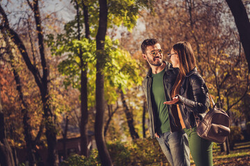 Poster - Photo of positive two hipsters girl guy talk in yellow september outdoors park wear leather jacket rucksack