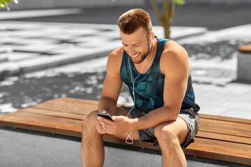 Poster - fitness, sport and technology concept - young athlete man with earphones and smartphone listening to music outdoors