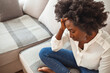 © Dragana Gordic - Close up african female sit on couch feels unhappy desperate thinking about personal difficulties mental health problems, 30s sad woman need psychological support goes through divorce break up concept