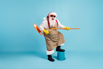 Wall Mural - Full length body size view of cheerful crazy Santa cleansing floor doing domestic housework duty using mop like instrument having fun fooling isolated bright vivid shine vibrant blue color background