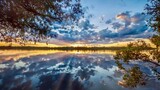 Fototapeta Tęcza - A beautiful and dramatic summer sunset with clouds and sunbeams reflected on a small lake in Ontario, Canada.