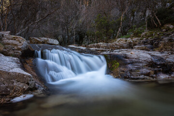 Wall Mural - River water flows among the rocks and forms small waterfalls, Rascafría, Madrid, Spain