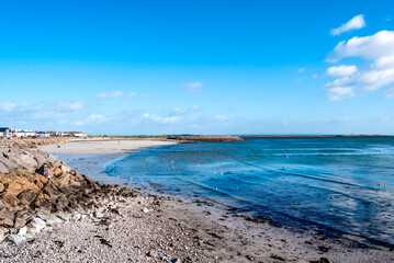 Wall Mural - The coast in Salthill overlooking Galway Bay, Ireland, along the Promenade in a sunny bright day, with sand, rocks and blue cristalline water.