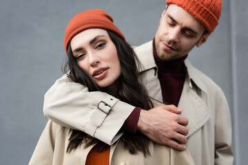 Sticker - selective focus of man looking and hugging stylish woman in hat