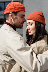 Wall Mural - stylish couple with closed eyes in trench coats and hats