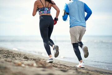 Wall Mural - Young female boxer and her coach jogging on the beach