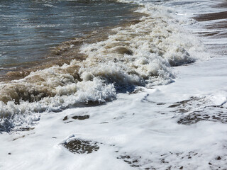 Huge stormy waves crashing near city embankment, dramatic sky on background. Big sea wave splash