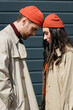 © LIGHTFIELD STUDIOS - side view of stylish couple in trench coats and hats leaning on each other outside