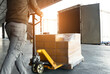 Workers Using Hand Pallet Jack Unloading Package Boxes into Shipping Cargo Container. Delivery Shipment Boxes. Trucks Loading at Dock Warehouse. Supplies. Warehouse Shipping Transport and Logistics.