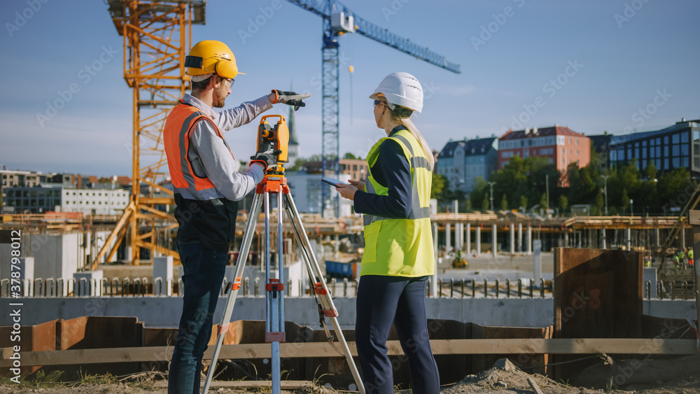 Construction Worker Using Theodolite Surveying Optical Instrument for Measuring Angles in Horizontal and Vertical Planes on Construction Site. Engineer and Architect Using Tablet Next to Surveyor. - obrazy, fototapety, plakaty 