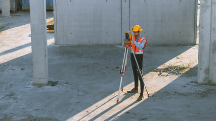 Wall Mural - Construction Worker Using Theodolite Surveying Optical Instrument for Measuring Angles in Horizontal and Vertical Planes on Construction Site. Worker in Hard Hat Making Projections for the Building.