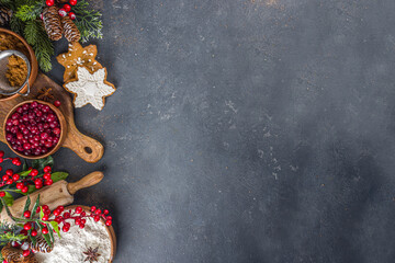 Wall Mural - Ingredients for Christmas cooking, winter baking cookies, gingerbread, fruitcake, seasonal drinks. Cranberries, dried oranges, cinnamon, spices, flour on dark stone table, copy space top view