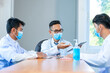 © visoot - Group of doctor wearing protective surgical mask and discussing work together at the table during meeting at hospital,Epidemic virus outbreak concept.
