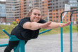 © Михаил Решетников - Fat young woman doing back extension exercise on exercise machines on the sports ground outdoors.