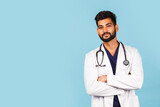 Fototapeta Do pokoju - Handsome modern Indian / Asian doctor with stethoscope, in uniform on blue background