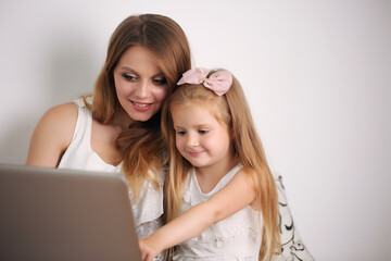 Poster - young mother works with her daughter on the pc at home