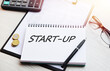 © Tatyana - The inscription START-UP. Handwritten text in a notebook on the background of financial tables.