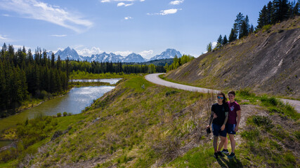 lesbian couple in front of a road leading to the grand tetons mountain range