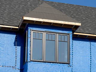 blue house wrap vapor barrier frames a window on a new residential construction project