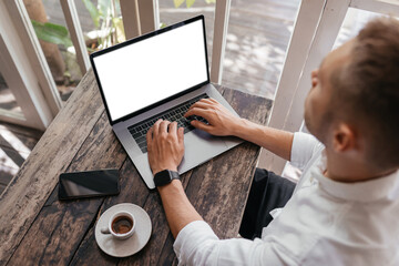 Cropped view of man with laptop computer th copy space for your text or promotional content, mobile phone, having coffee, sitting at a cafe