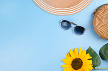 Fashion Flatlay With Sunglasses, Straw Boater Hat And Bright Big Yellow Sunflower On Blue Background. Flatlay Style.