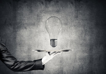 Wall Mural - Hand of waitress presenting lightbulb on tray.