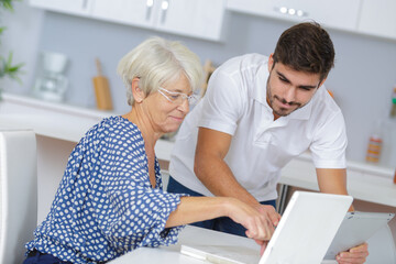 Wall Mural - youngerman helping an elderly person using laptop computer