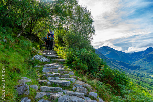 Fotomural People walking up the hiking trail of Ben Nevis mountain, Scotland, UK with a be
