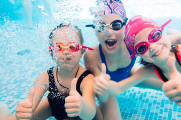 Underwater photo of young friends in swimming pool.