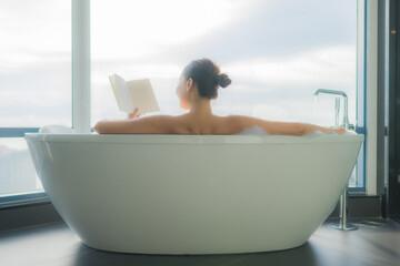 Portrait beautiful young asian woman read book in white bathtub