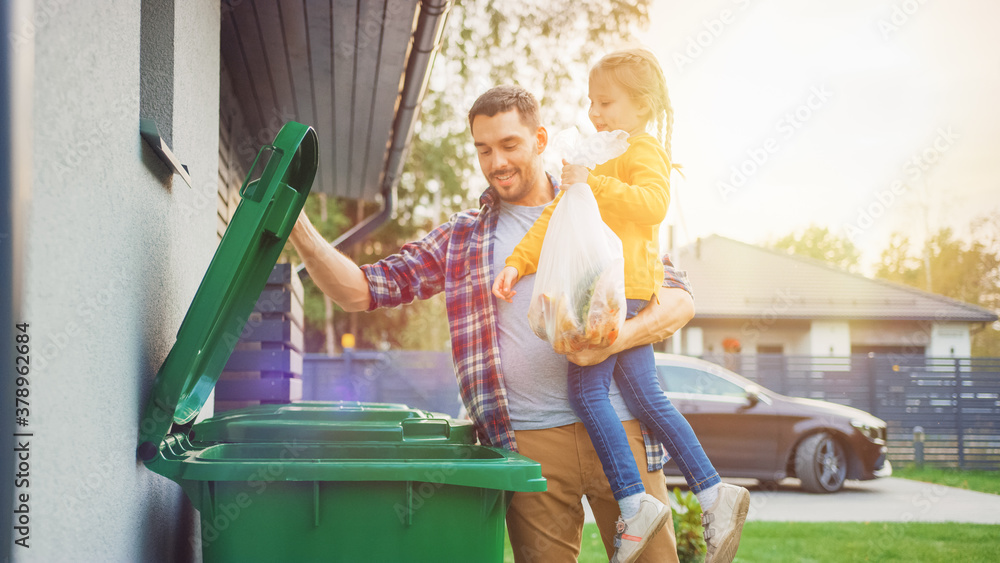 Father Holding a Young Girl and Throwing Away a Food Waste into the Trash. They Use Correct Garbage Bins Because This Family is Sorting Waste and Helping the Environment. - obrazy, fototapety, plakaty 
