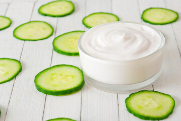 Wall Mural - Moisturizer with cucumber slices on white wooden