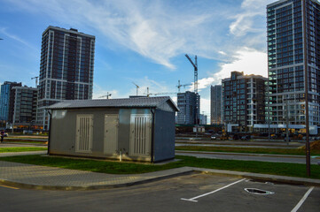 Wall Mural - electrical house with power lines. concrete house with insulation and air conditioning for electricity shields. against the background of glass houses of a new residential complex