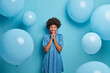 © wayhome.studio  - Fashionable dark skinned woman in polka dot dress stands smiling against blue background decorated for special occasion. Birthday girl happy to get congratulations. Party and celebration concept