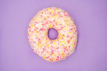 Top view of a delicious glazed donut with sprinkles isolated on a purple background