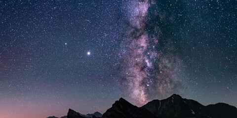 Wall Mural - the milky way core and glowing stars in the night sky oover the alps. panoramic view high mountain r