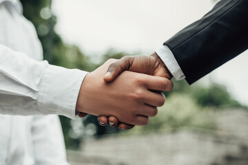 Close up view of two young entrepreneurs. African american male shaking hands with european man. Career and entrepreneurship concept with copy space. Satisfaction after transaction.