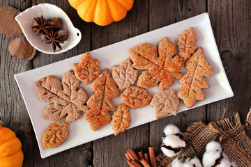 Wall Mural - Autumn table scene with spiced leaf cookies. Top view on a rustic wood background.