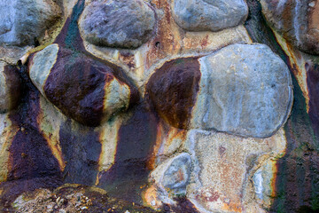 Colorful stone surface closeup photo with wet stain. Stone wall texture for natural rustic background. Dirty water stain