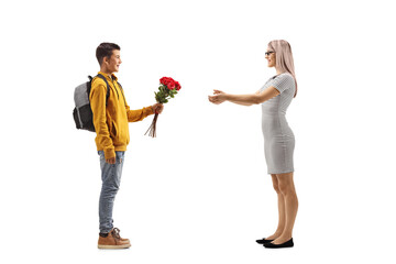 Wall Mural - Full length profile shot of a teenager  schoolboy giving a bunch of red roses to a woman
