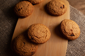 Oatmeal cookies with chocolate chips lie on a wooden board.