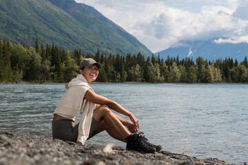 Young woman sit and relax on the mountain lake wearing sport clothes in Alaska trip