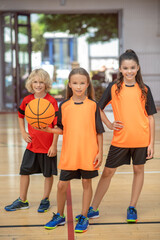 Wall Mural - Kids in sportswear standing with a ball and looking contented