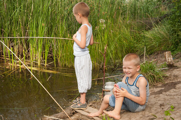 Funny children in colorful clothes took fishing rod and try to fish near river in the reeds. Funny situations while fishing. Summer vacation in village. Brothers are happy together