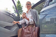 © Kostiantyn - Beautiful smiling middle aged business woman with handbag holding cup of take away coffee while getting out of her modern car