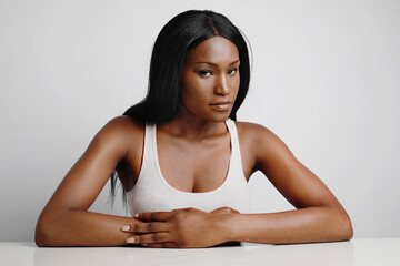 Wall Mural - Portrait of young Afro black woman, with perfect skin and long hair. Posing over grey background. 