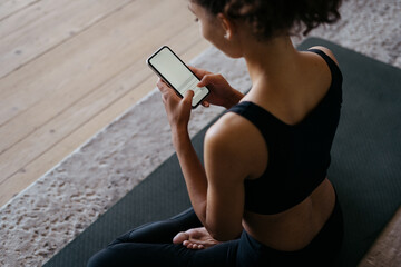 Adult african american athletic woman using modern smartphone