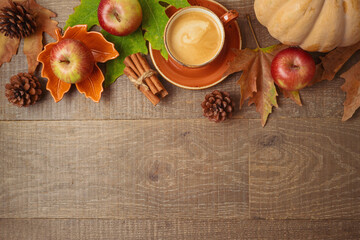 Wall Mural - Autumn season concept with coffee cup, apples, pumpkin and fall leaves on wooden table background