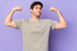© Asier - Young man isolated on purple background showing strength gesture with arms, symbol of feminine power