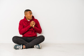 Wall Mural - Young latin man sitting on the floor isolated scared and afraid.